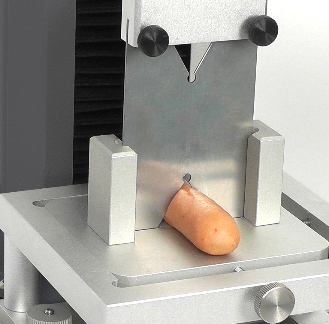 Hot dog tenderness texture test with Warner-Bratzler meat industry blade fixture.